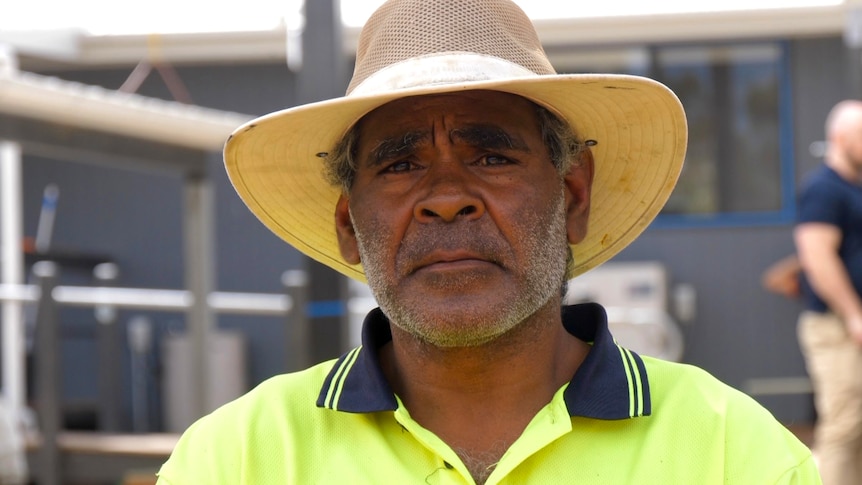 An aboriginal man wearing a broad-brimmed hat with a hi-vis yellow collared shirt