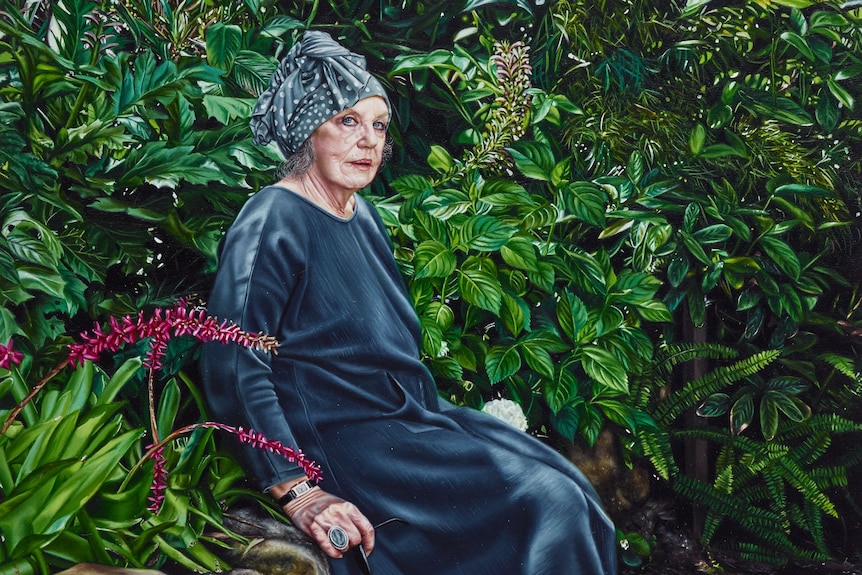 A portrait of a woman in a green dress sitting in her garden
