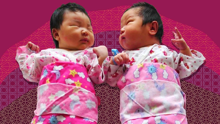 Two Chinese babies wrapped in cute star, moon and cloud blanket.