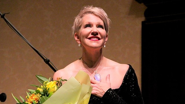 Mezzo-soprano Joyce DiDonato smiling and holding a bouquet on stage at Wigmore Hall.