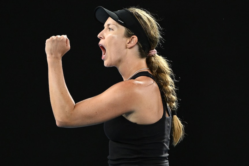 An American female tennis player pumps her fist as she celebrates winning a point.