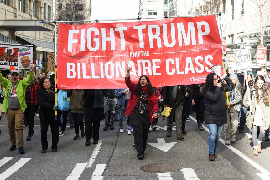 Protesters march with a sign reading "Fight Trump and the Billionaire Class"