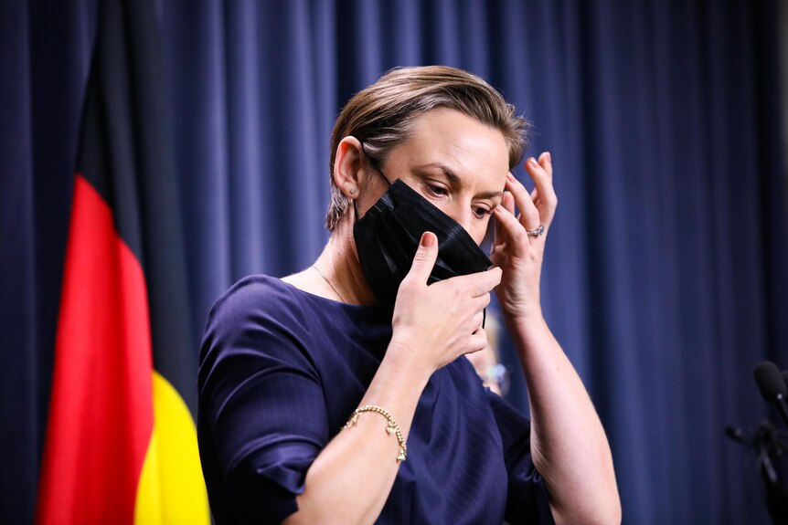 A woman with short hair taking her mask off.