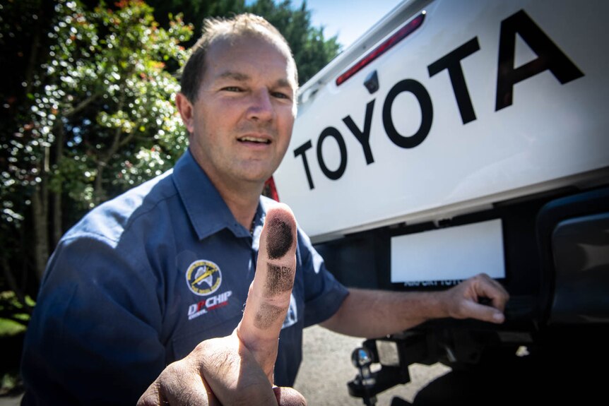 Diesel mechanic Andrew Leimroth with black soot on his finger from the exhaust tailpipe of a Toyota Hilux