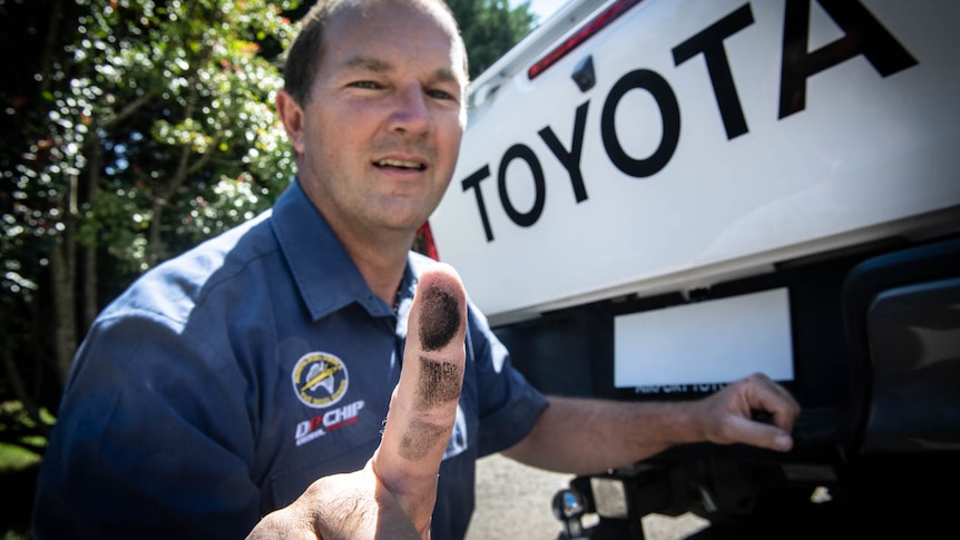 Diesel mechanic Andrew Leimroth with black soot on his finger from the exhaust tailpipe of a Toyota Hi-Lux vehicle.