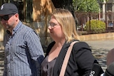 A woman with short blonde hair and glasses walking outside Adelaide's Magistrates Court. 
