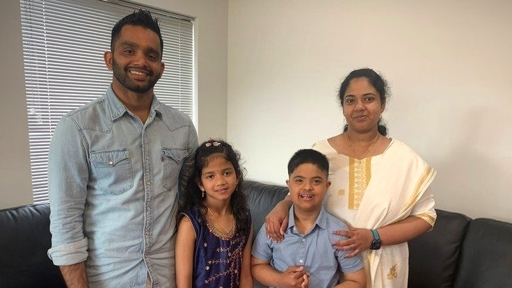 A family of four standing in a living room