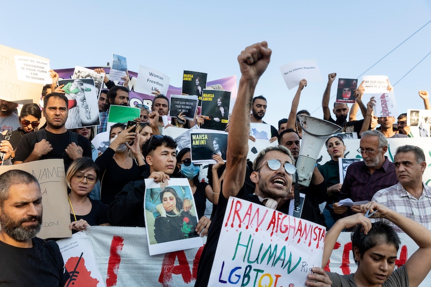 Protesters shout slogans and hold up placards against Iran's government during a protest in Athens.