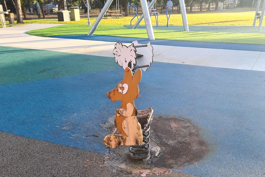 A child's playground kangaroo rocker stands, scorched