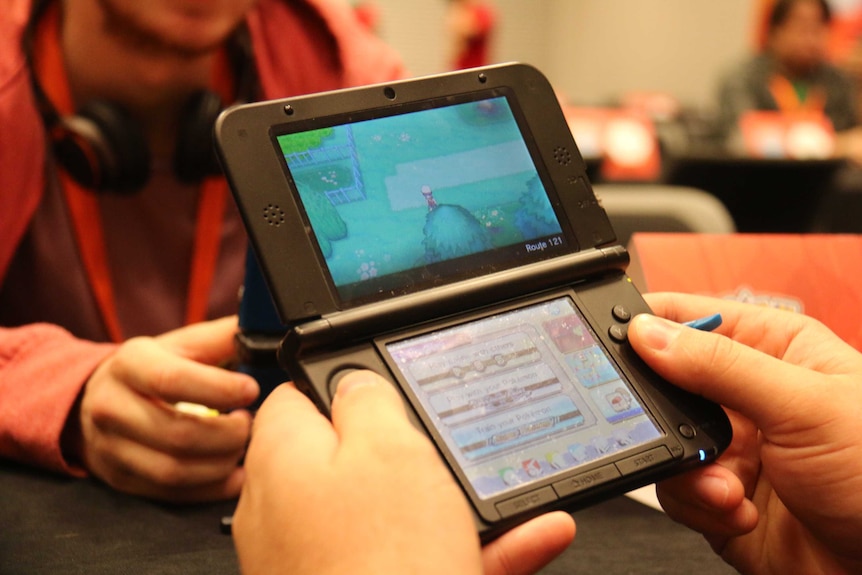 Close up of man playing a Pokemon game on the Nintendo 3DS
