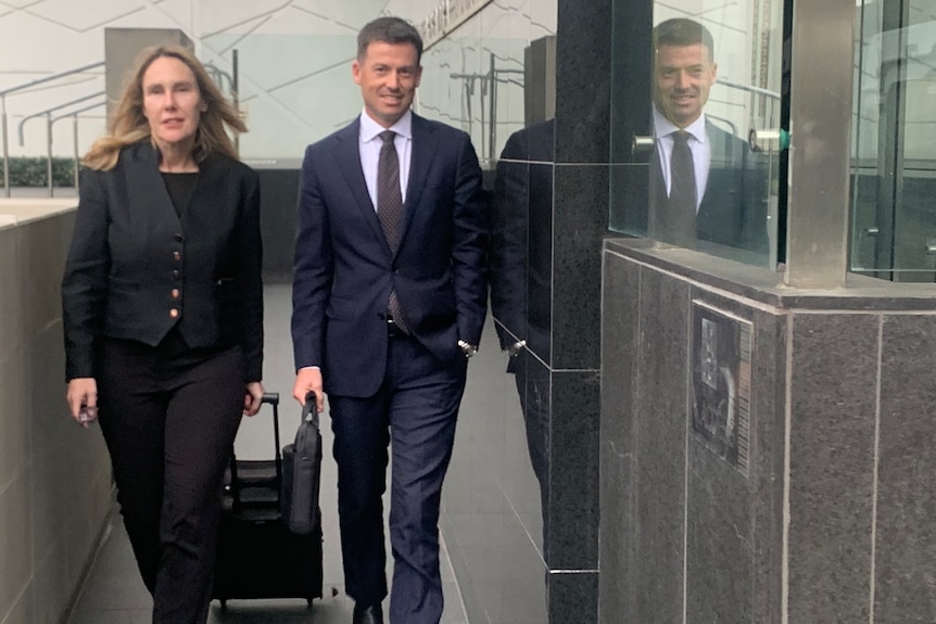 A female lawyer walks next to her male colleague outside court