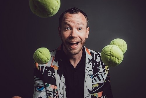 A comedian in action with many juggling suspended balls in the air