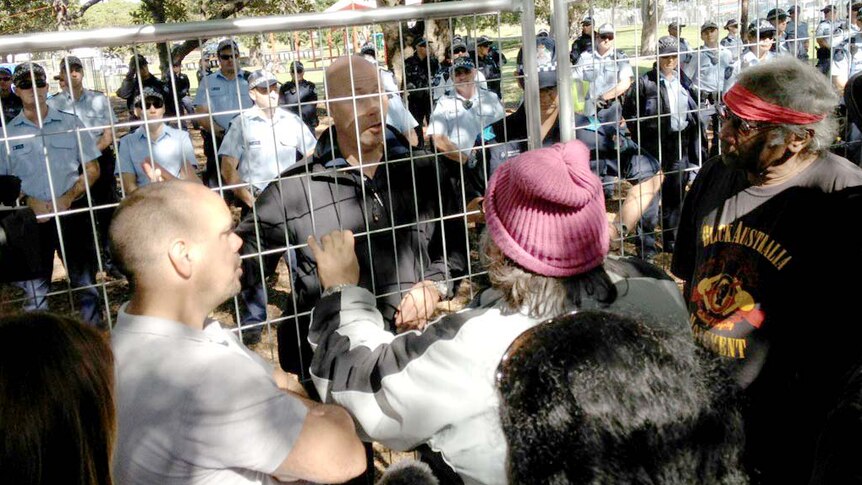 Police and protesters talk through a barricade in South Brisbane's Musgrave Park