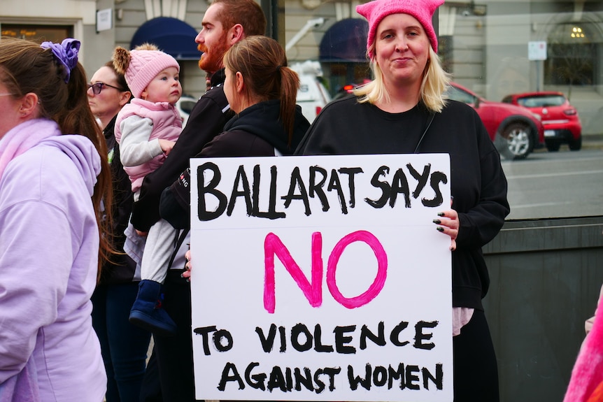 a blonde woman holds a sign