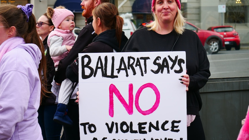 a blonde woman holds a sign