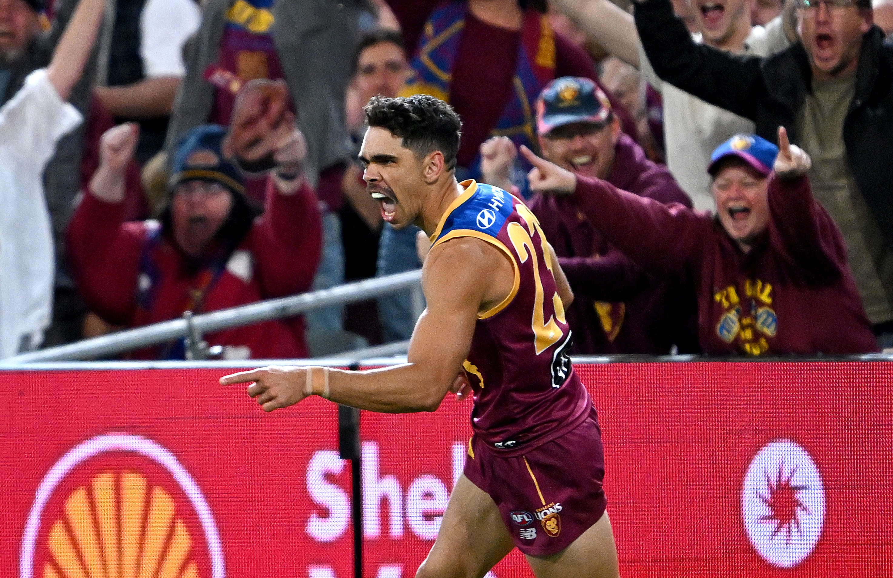 Brisbane Lions forward Charlie Cameron sprints away from goal, with his finger pointed in celebration as the crowd cheers. 