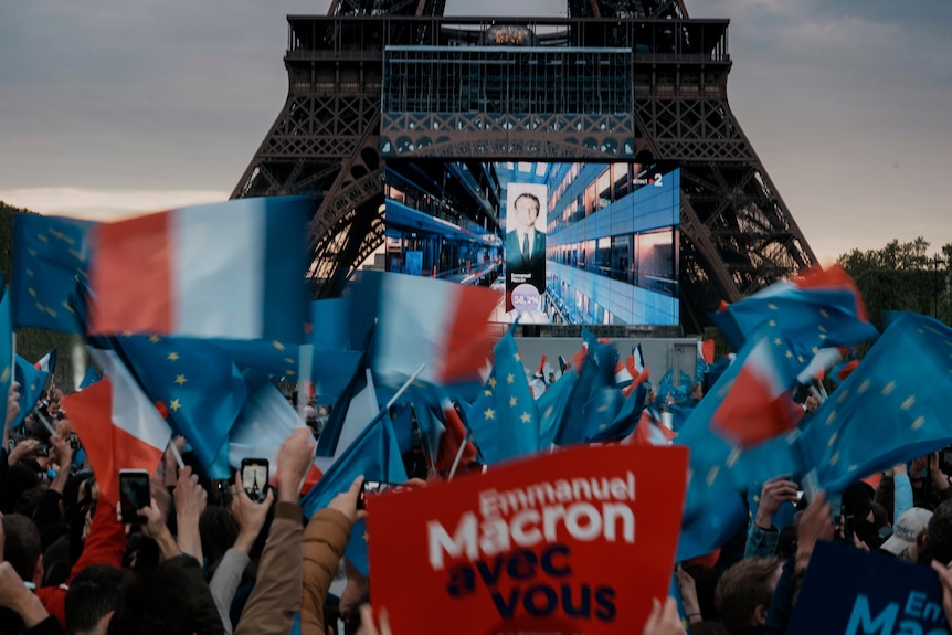 First election projections are shown on a screen in front of the Eiffel Tower in Paris.