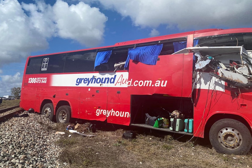 A red bus on the side of a rural highway. The front of the bus is significantly damaged.