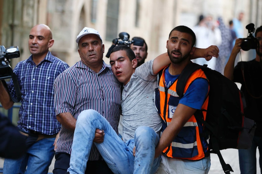 A Palestinian youth is evacuated after being injured during clashes between Palestinians and Israeli police at Jerusalem's flashpoint Al-Aqsa mosque