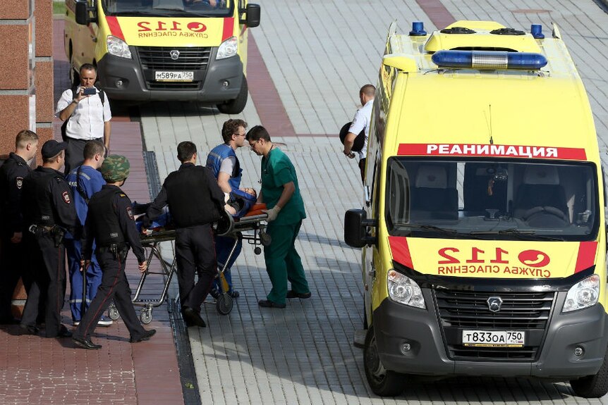 A man on a stretcher and surrounded by medics and security is taken to a waiting ambulance outside the court.
