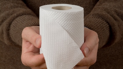 A person holding a roll of toilet paper