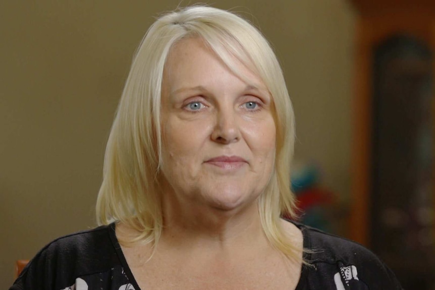 Head shot of Desiree Sheets-Chavolla wearing a black printed t-shirt and blurred cabinet in the background