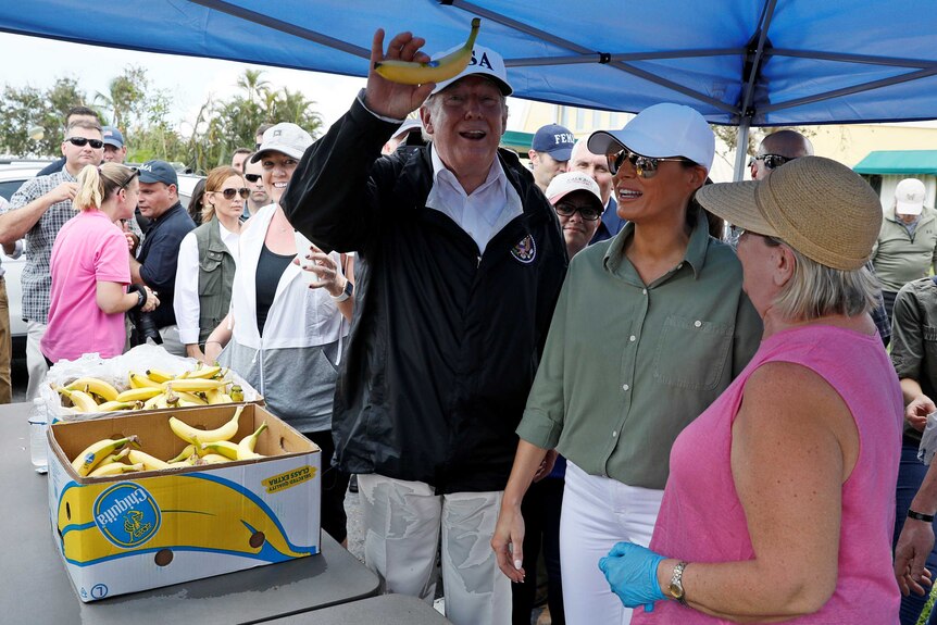 US President Donald Trump holds up a banana while distributing food.