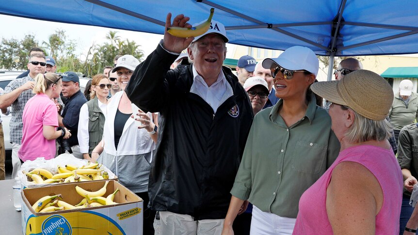 US President Donald Trump holds up a banana while distributing food.