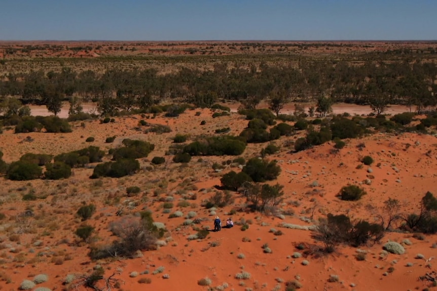 Photo of the desert with people sitting on sand