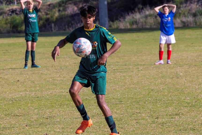 Un jeune garçon joue au football avec un ballon devant lui