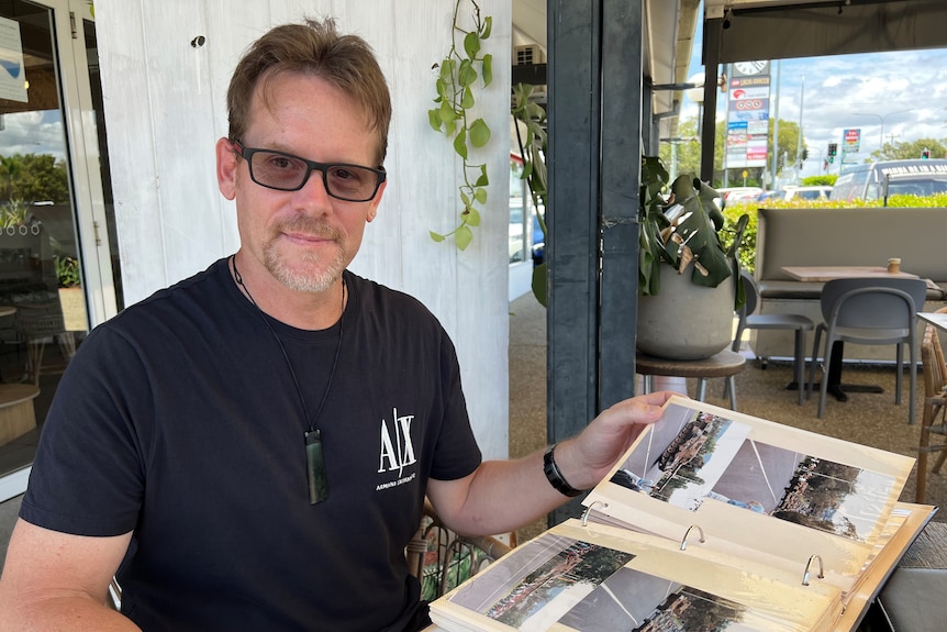 A man at a cafe flips through a photo album