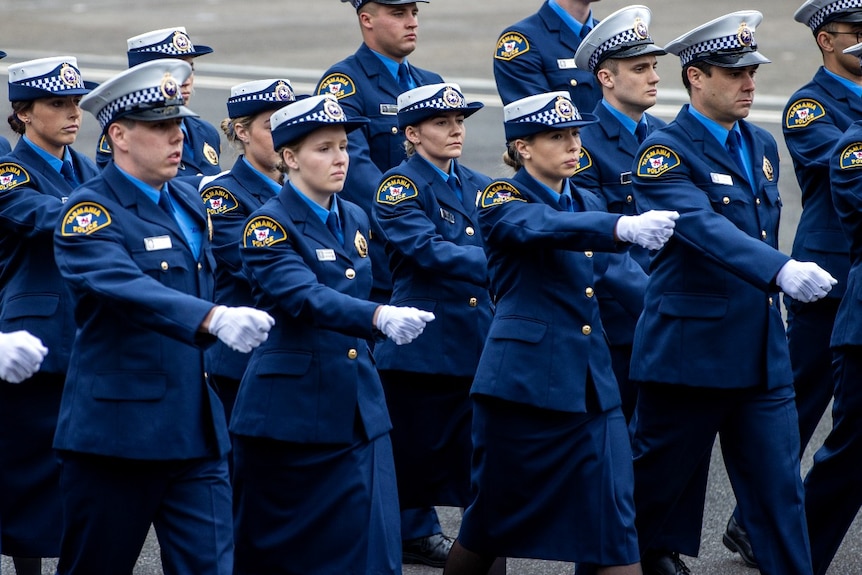A group of people in blue uniform march past the camera