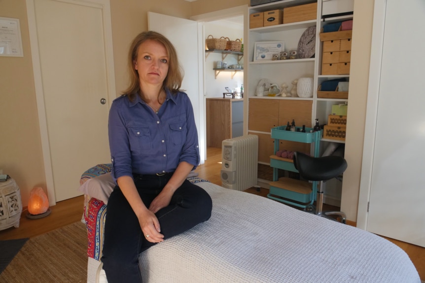 Woman sits on a massage bed in a therapy room