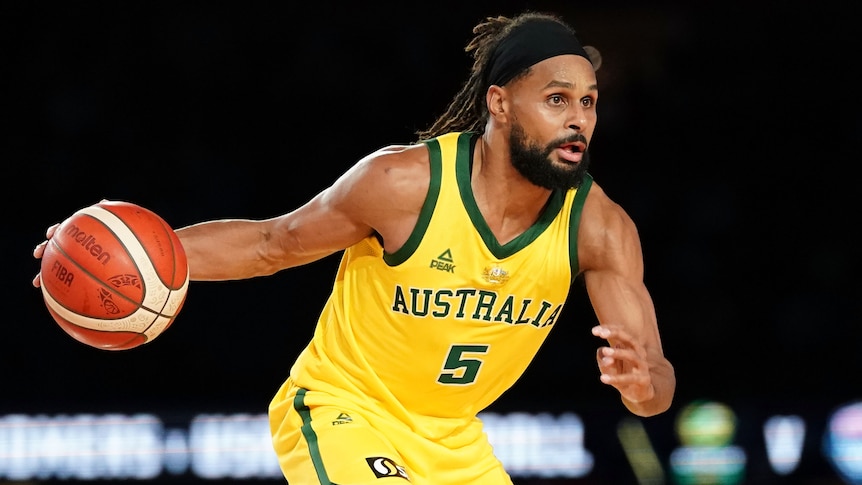 An Australian male basketballer dribbles the ball with his right hand.