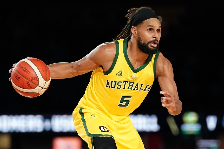 An Australian male basketballer dribbles the ball with his right hand.