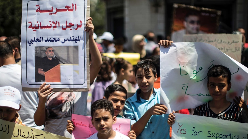 Palestinian children hold signs protesting the arrest of a World Vision employee.