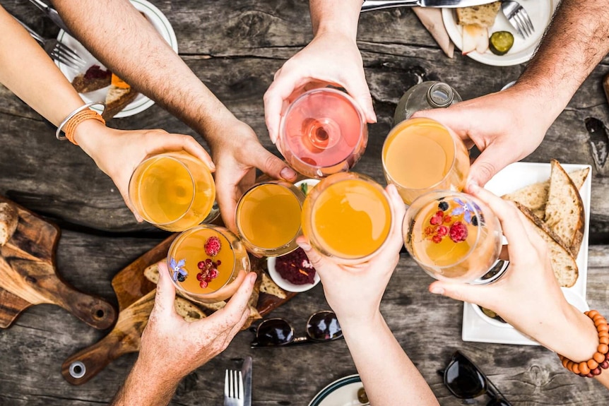 hands holding different glasses of cider