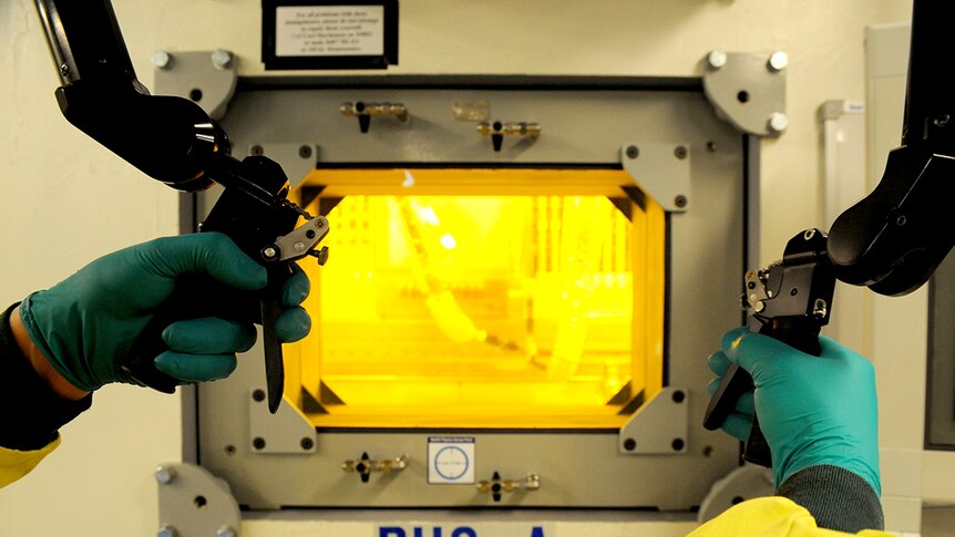 A technician uses a hot cell which shields radioactive material.