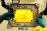 A technician uses a hot cell which shields radioactive material.