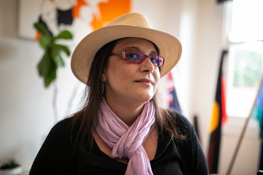 A woman in red glasses and a hat and a pink scarf