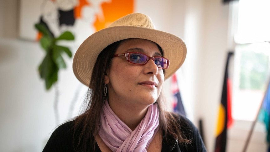 A woman in red glasses and a hat and a pink scarf