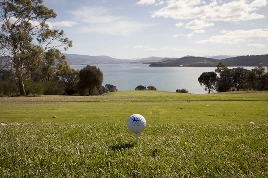 A golf ball in the forefront of the view from Tasmania Golf Club.