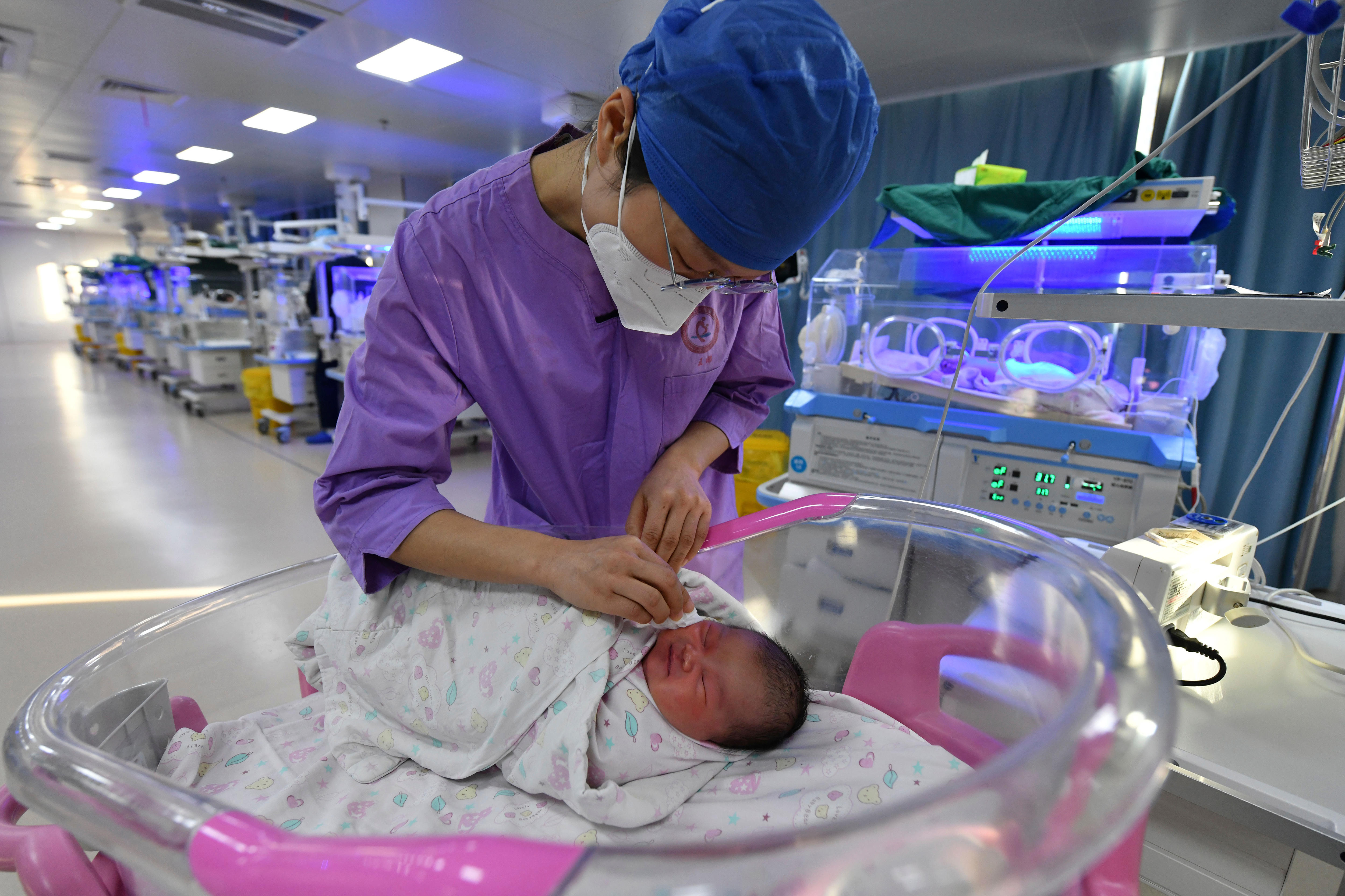 A nurse tends to a newborn inside a maternity ward.