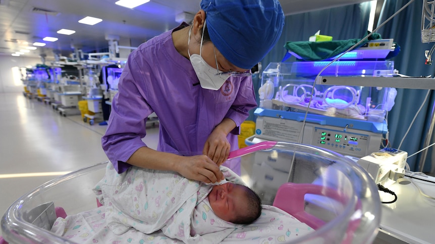 A nurse tends to a newborn inside a maternity ward.