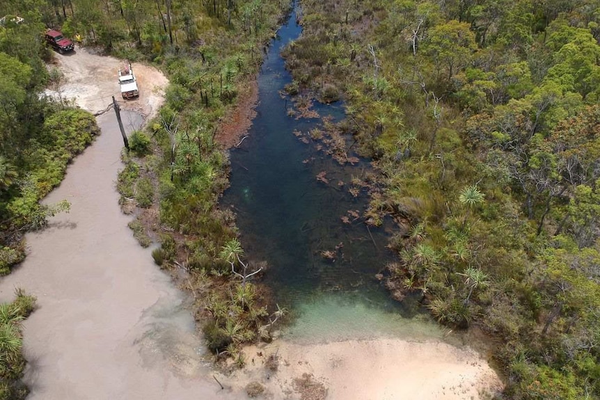 Aerial photo of 4WDs approaching creek surrounded by vegetation
