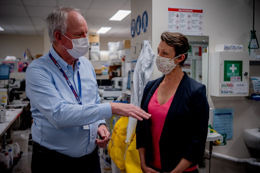 Mary Lloyd talking a pathologist in St Vincent's hospital, both wearing face masks.