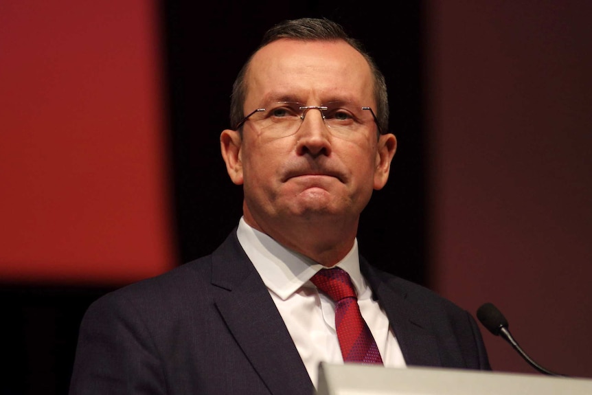 A head and shoulders shot of WA Premier Mark McGowan on stage speaking at Labor's state conference in a suit, tie and glasses.
