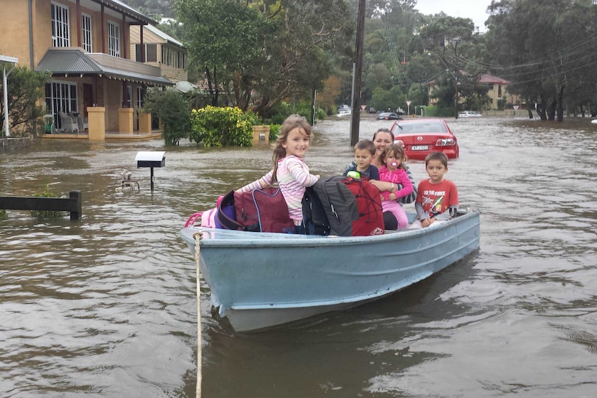 The Popovski family use a dinghy to escape flooding at their house in Narrabeen