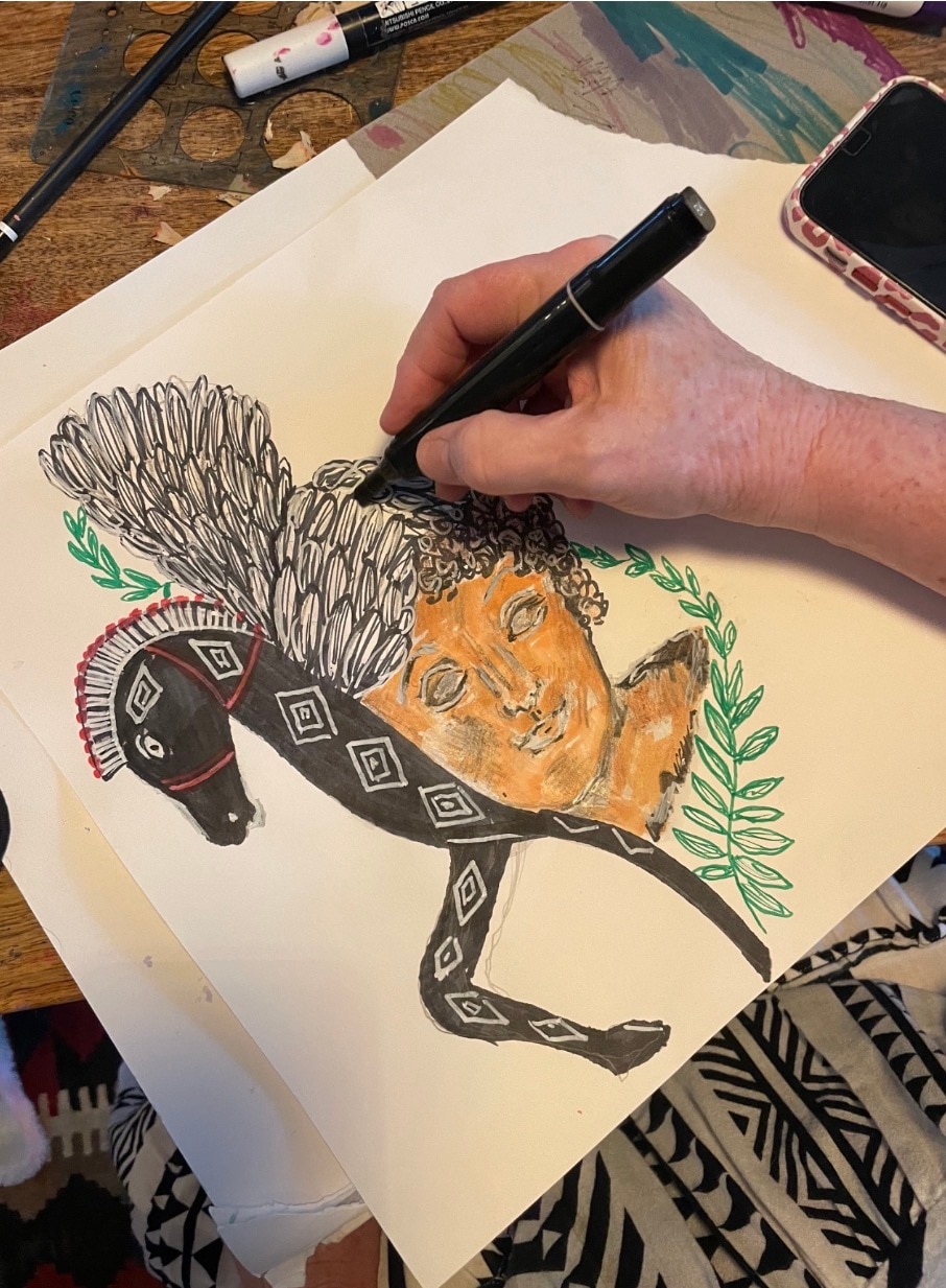 A hand drawing a horse and head design. 