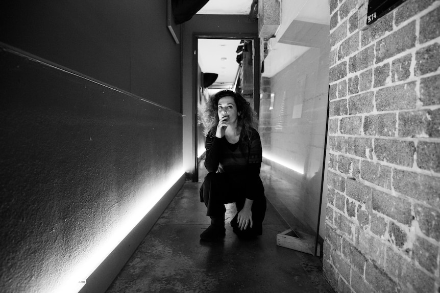 Leah Flanagan crouches in a narrow corridor